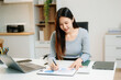 © Nuttapong punna - Asian Businesswoman Analyzing Finance on Tablet and Laptop at modern Office Desk