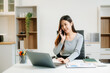 © Nuttapong punna - Young attractive Asian woman smiling thinking planning writing in notebook, tablet and laptop working from home