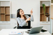 © Nuttapong punna - Young attractive Asian woman smiling thinking planning writing in notebook, tablet and laptop working from home