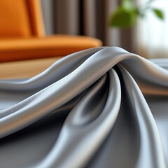 Leinwandbilder - Close-up shot capturing the elegant folds of a silver cloth, bathed in soft light. An orange sofa adds a pop of color in the background, complemented by the subtle greens of a potted plant, creating