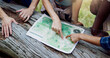 © peopleimages.com - Map, nature and hands of people hiking in forest with route plan for adventure together. Travel, above and friends with paper guide for trekking in woods on weekend trip for discovery or journey.