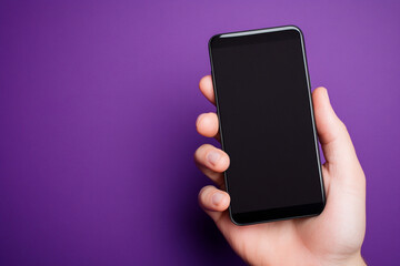 Hand holding smartphone black screen purple background