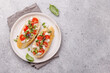 © evgeeenius - Tasty antipasto toasts featuring classic caprese with mozzarella and tomatoes, and savory prosciutto with herbs