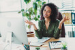 © deagreez - Confident young businesswoman in casual attire smiling at her office desk