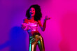 © deagreez - Cheerful young woman in shiny outfit performing with a microphone in vibrant purple and pink neon lighting, exuding energy