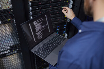technician resolving technical issues in a data center equipped with servers and monitoring laptop. 
