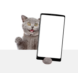 Aufkleber - Surprised cat holding big smartphone with white blank screen and looking above blank banner. Empty free space for mock up. Isolated on white background