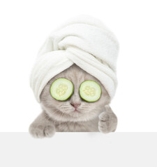 Fototapete - Funny kitten with towel on it head and with slices of cucumber on it eyes looks above blank white banner and shows thumbs up gesture. isolated on white background