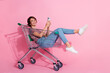 © deagreez - Photo of charming cheerful positive lovely girl wear stylish clothes sitting pushcart chatting isolated on pink color background