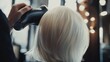 © aisyah - Professional hairstylist using blow dryer to style short blonde hair in salon