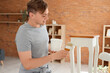 © Pixel-Shot - Young man with brush and can painting table at home