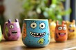 © Michael - Colorful ceramic mugs with funny monster faces smiling on a wooden table