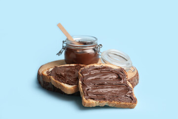 Wall Mural - wooden board of toasts with sweet chocolate spread on blue background