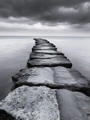 Poster - Dramatic Black and White Image of a Stone Pathway Leading into a Calm Seaside Horizon : Generative AI