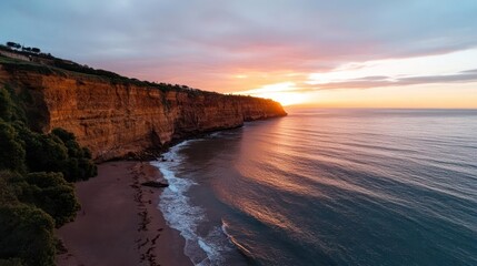 Aufkleber - Scenic aerial view of a cliffside meeting the ocean at sunset, featuring a sandy beach, lush greenery, and the sun casting a warm glow on the water and rock formations