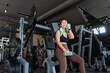 © 2B - Woman exercising in a gym, taking a break while smiling and wearing workout attire