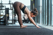 © 2B - Woman practicing yoga in a fitness studio during a morning workout session, focusing on forward bend position for flexibility