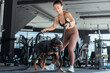 © 2B - Woman exercises with dog using battle ropes in a modern gym environment during daytime