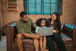 © chokniti - Heartwarming family moment as an African American father and daughter share playful time together on the couch, surrounded by love, laughter, and the warmth of home, while mom gently looks on with joy