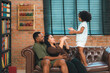 © chokniti - Heartwarming family moment as an African American father and daughter share playful time together on the couch, surrounded by love, laughter, and the warmth of home, while mom gently looks on with joy