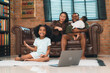 © chokniti - Heartwarming family moment as an African American father and daughter share playful time together on the couch, surrounded by love, laughter, and the warmth of home, while mom gently looks on with joy
