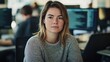 © Daiki - A focused young European woman sits in a modern office setting. Her serious expression reflects concentration while working on a computer, embodying professionalism and determination.