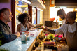© Marko Geber - Chefs serving sushi to smiling customers at Japanese restaurant counter