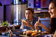 © Marko Geber - Asian man using phone while friends eat sushi at restaurant table