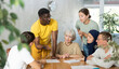© JackF - Adult African American male tutor conducting lesson for group of interested adult people of different nationalities sitting around table in classroom in foreign language school..