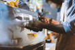 © Prostock-studio - Barista make coffee with espresso machine in cafe and social distancing. Focus on african american man in apron works with equipment, doing drink for client during coronavirus outbreak, cropped
