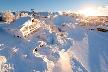 Leinwandbilder - A serene winter landscape unfolds with a snow-covered building nestled on a hill, bathed in the warm glow of the sun. The scene is dominated by white snow, contrasting with the clear sky and the