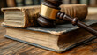 © Swaha - Gavel resting on aged law books, symbolizing justice, law, history, and legal proceedings.  A close-up shot highlighting texture and detail.