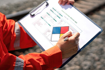 Wall Mural - close-up at safety supervisor's hand during writing on chemical safety checklist to verify the hazar