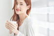 © Dialogue Frame - Young Woman Smiling with Coffee Cup Indoors