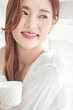 © Dialogue Frame - Young Woman Smiling with Coffee Cup Indoors