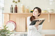 © Dialogue Frame - Young Woman Reading Book in Bright Modern Kitchen
