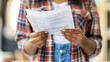 © Xinfang - Distressed immigrant holding folded legal document with anxious expression, immigration law and citizenship process concept, legal rights and human rights theme.