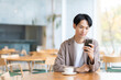 © dimlight - スマホを見てカフェでくつろぐ若い男性