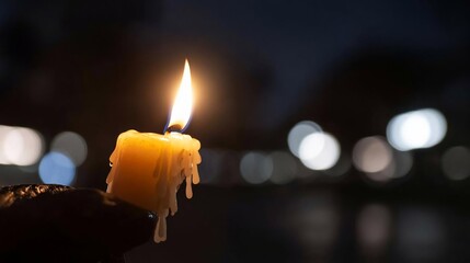 Aufkleber - Close-up shot of a hand holding a lit candle at night with blurred bokeh lights in the background creating a warm and intimate atmosphere