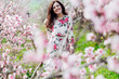 © dmitriisimakov - woman walking in flower dress in spring blooming garden