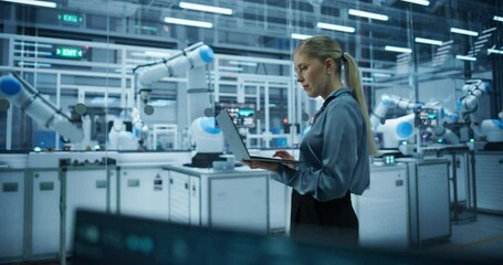 Leinwandbilder - Electronics Factory Manager Working on Laptop at an Industrial Manufacture with Robotic Arms. Female Specialist Monitoring Data on a Computer, Checking and Planning Production Process