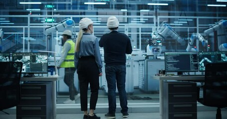 Fototapete - System Administrator and Technician Working at a Manufacturing Plant. Male Specialist Programming the Work of the Robotic Arms, Explaining Production on the Assembly Conveyor to a Female Colleague