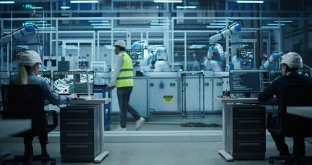 Leinwandbilder - Establishing Footage at an Electronics Factory with Robotic Arms. Diverse Engineers and Developers Working on Desktop Computers. Indian Worker in High Visibility Vest Pushing a Trolley with Equipment