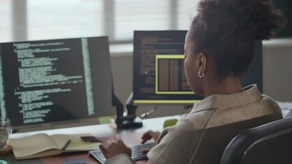Wall Mural - rear view zoom out shot of focused young african american female programmer typing code while workin