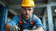 © useful pictures - Man wearing a yellow helmet and safety glasses is standing in a room. He is wearing a blue shirt and orange vest