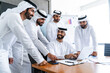 © oneinchpunch - Arab businessmen wearing emirati kandura meeting in office for business deal - Corporate business group of middle-eastern people working in an international company in middle east