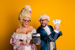 © deagreez - Two individuals in historical costumes humorously depicting royalty while holding a calculator and cash against a bright yellow background
