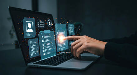 a person interacts with a laptop displaying digital data and interface elements in a dark environmen