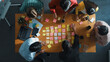 © InfiniteFlow - Top view of smart diverse business team working together and clapping hand while brainstorming marketing idea or creative startup project by using sticky notes and stick at meeting table. Convocation.