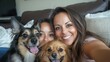 © elena - Mother and daughter taking a selfie with dogs on the sofa
